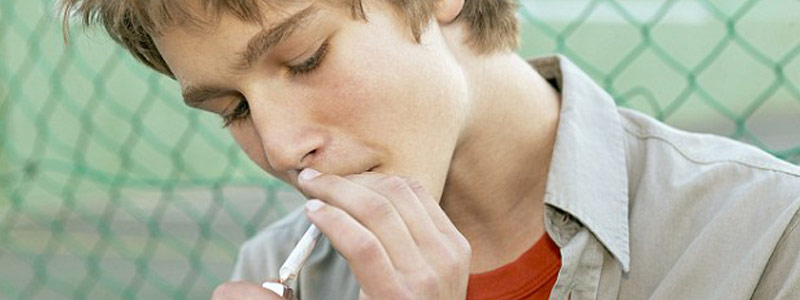 Молодой человек курит марихуану