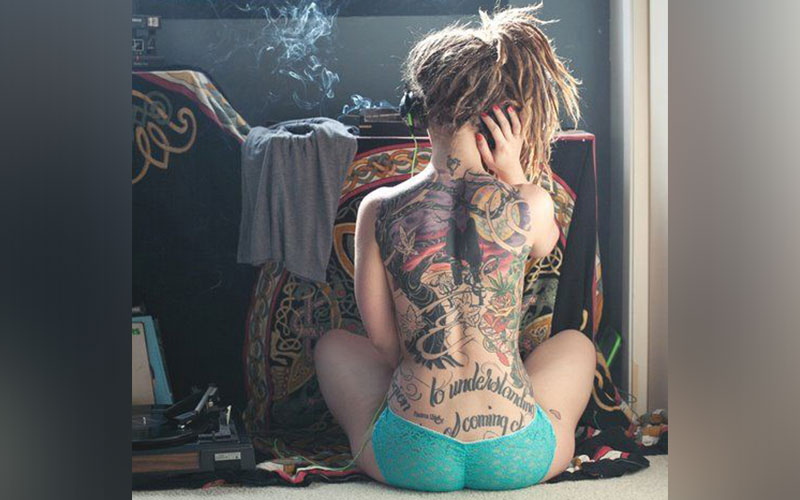 Спина курящей девушки в татуировках